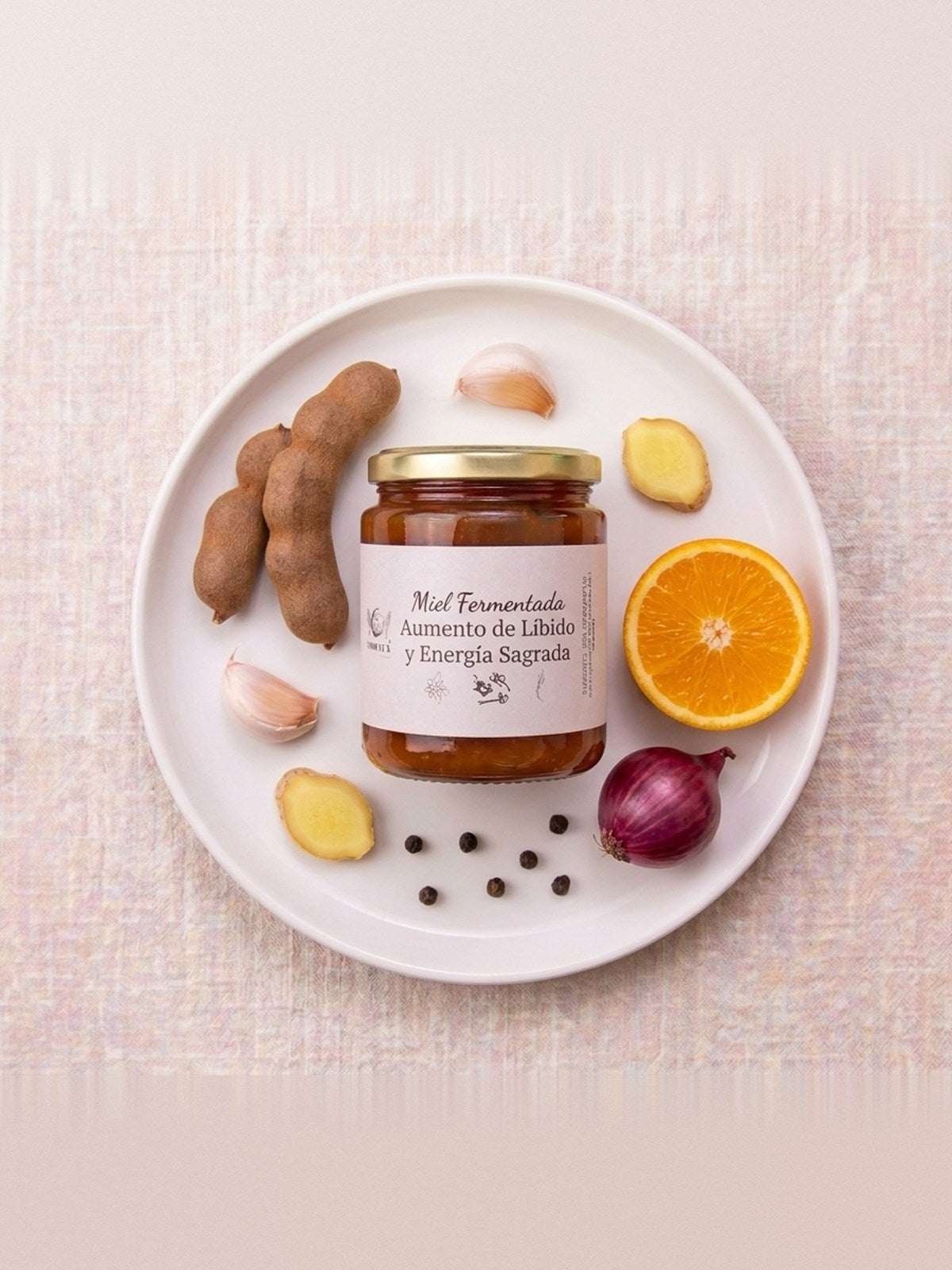 Frasco de miel fermentada Aumento de Líbido y Energía Sagrada sobre un plato con tamarindo, naranja y ajo