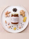 Frasco de miel fermentada Limpieza y Caída del Cabello sobre un plato con ajo, jengibre y pimienta